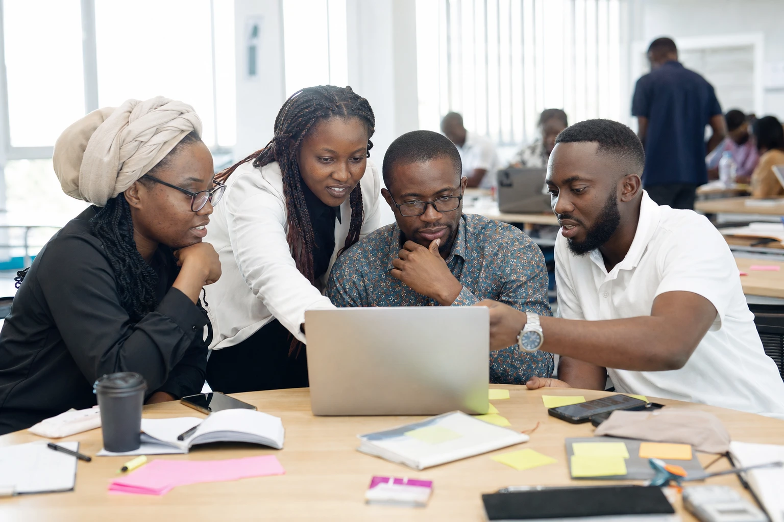 Professionals collaborating around a laptop during a working session
